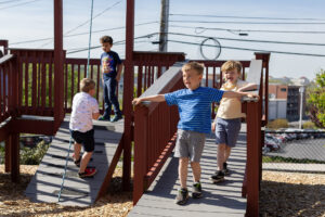 Children play in the sun on an outdoor play structure.